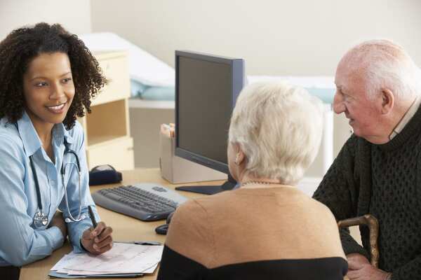 A GP talking to an elderly couple